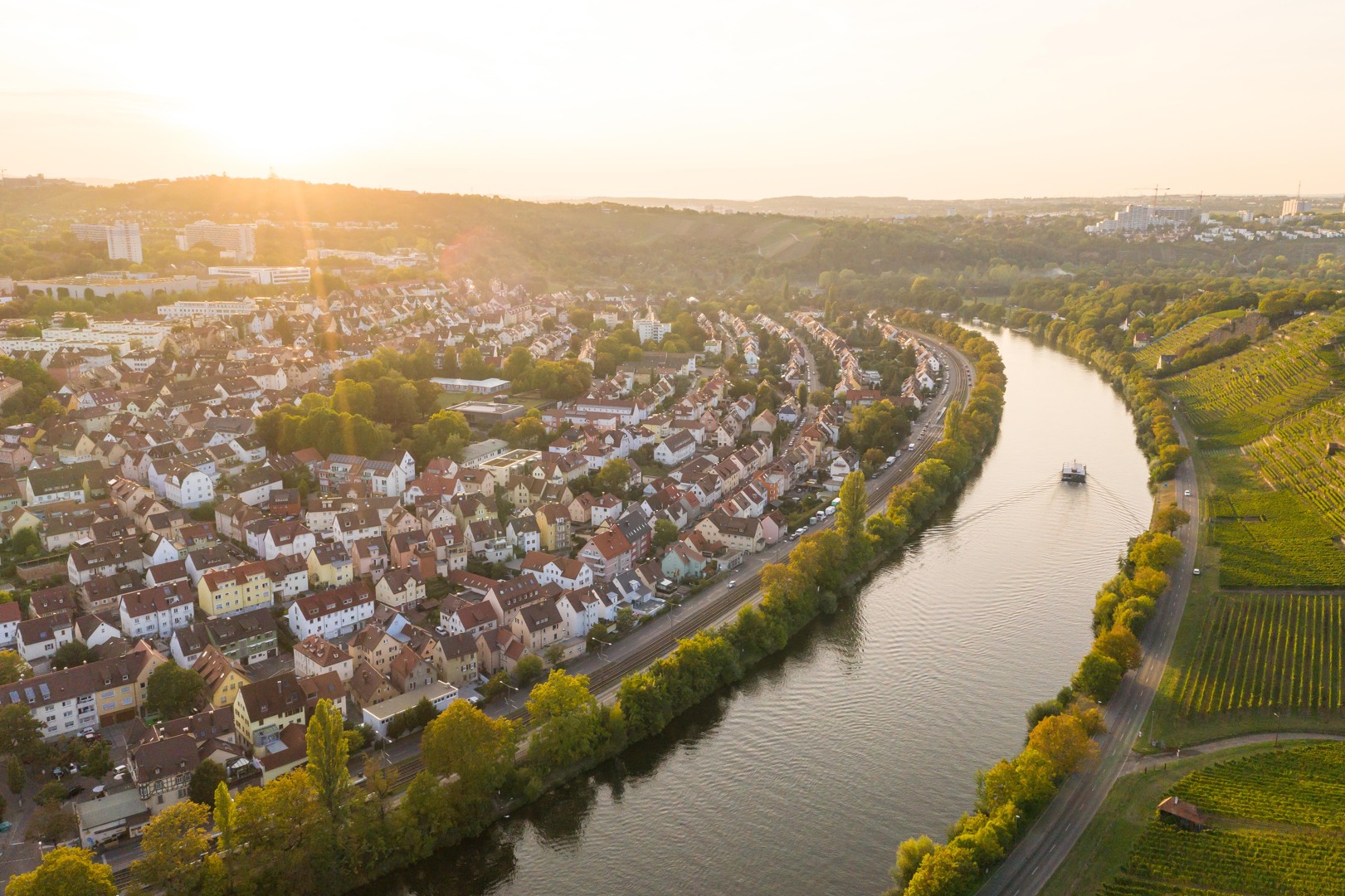 Das Schrägluftbild zeigt Teile des Stadtbezirks Münster und in der rechten Bildhälfte den Neckar und Weinberge in der Abendsonne. Foto: Max Kovalenko/Stadt Stuttgart