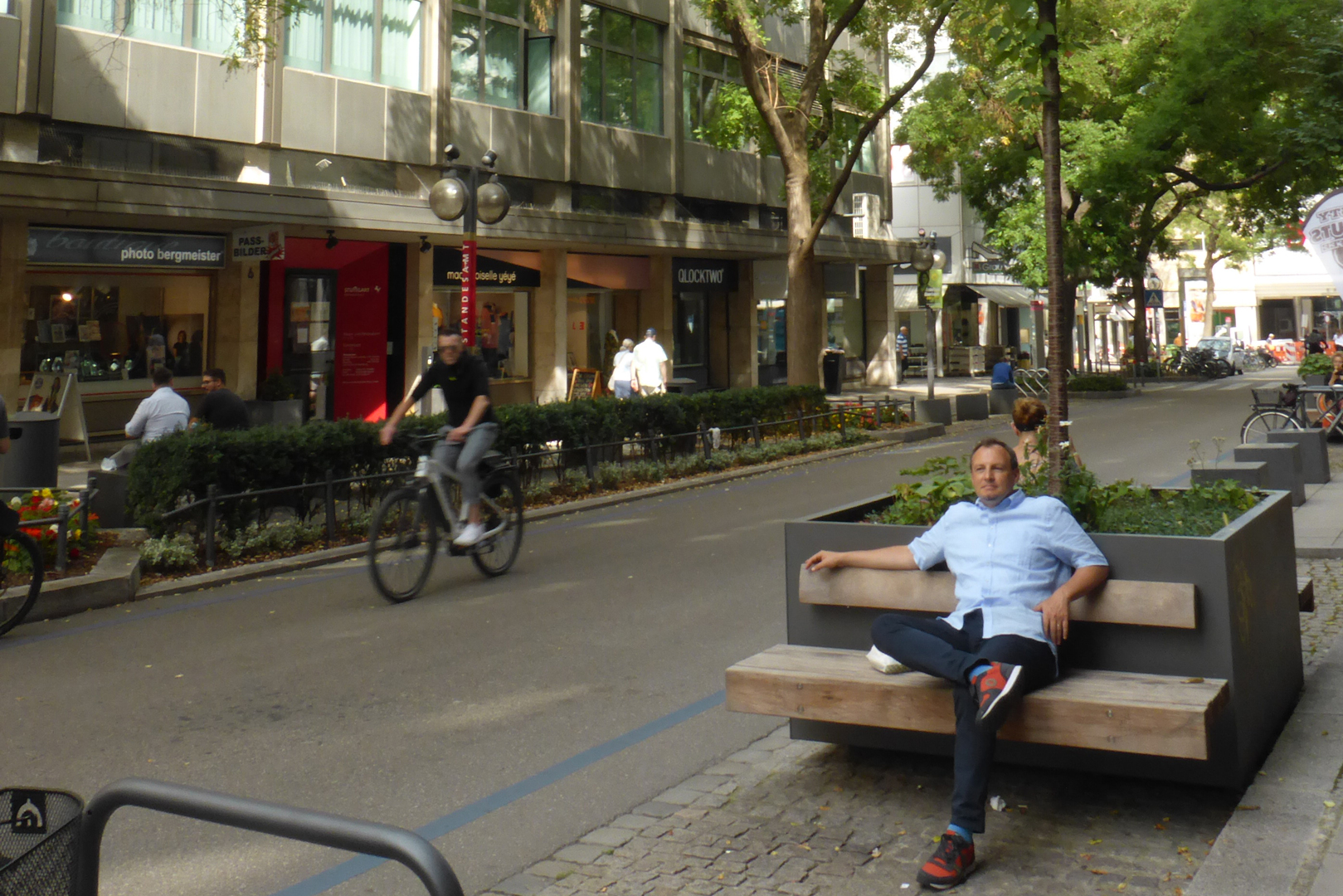 Blick in die Eberhardstraße. Eine Person sitzt auf einer Bank an einem Pflanzenkübel. Foto: Stadt Stuttgart