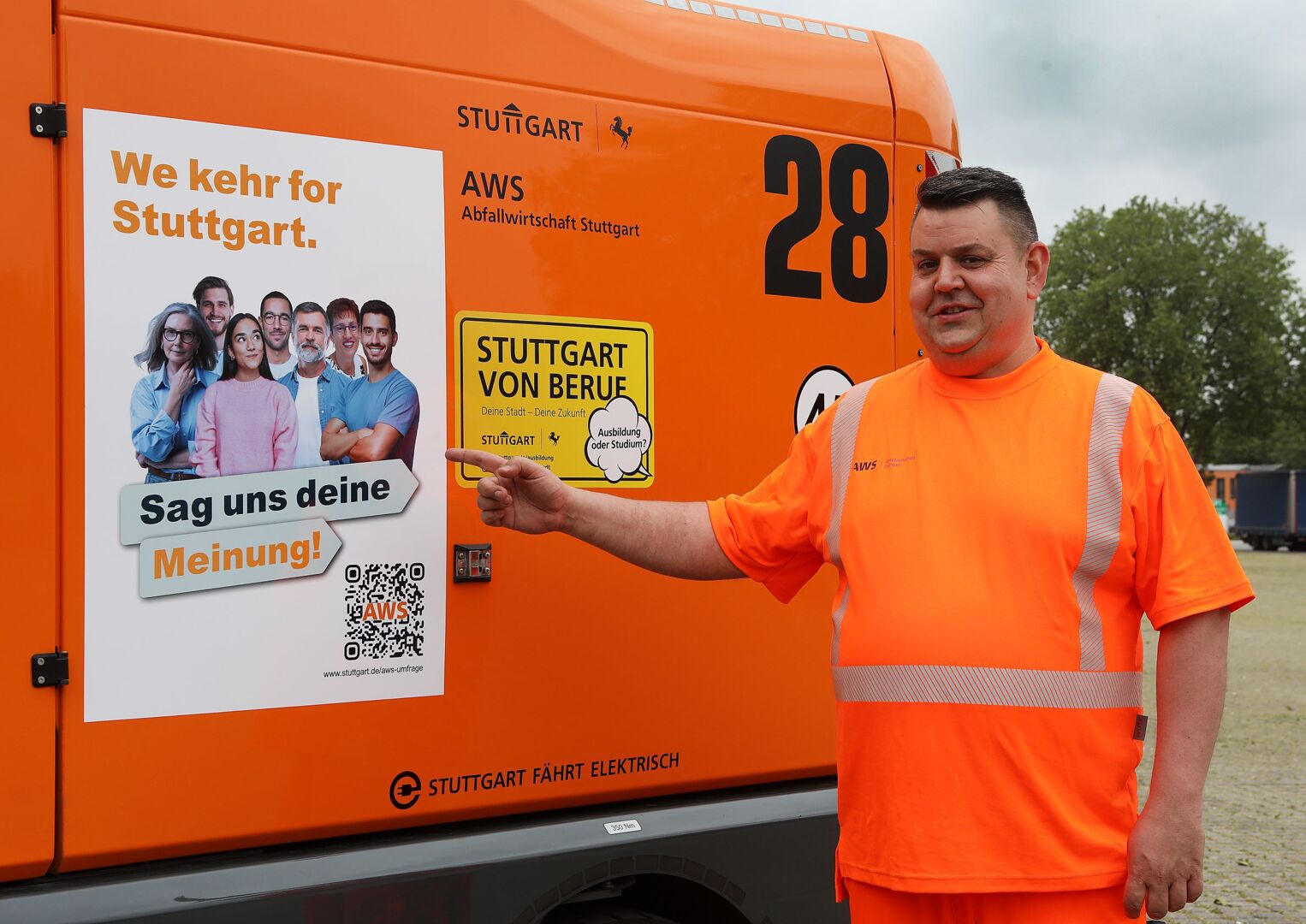 Ein M&uuml;llwerker steht vor einem Abfalltransporter und zeigt auf ein an dem Fahrzeug angebrachtes Plakat. Foto: Thomas H&ouml;rner/Stadt Stuttgart